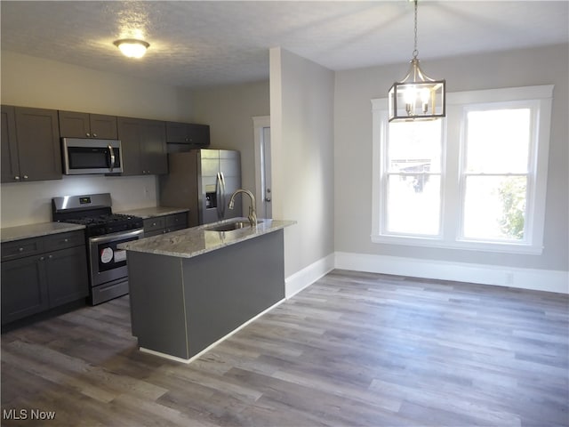 kitchen with dark hardwood / wood-style flooring, appliances with stainless steel finishes, light stone countertops, sink, and decorative light fixtures