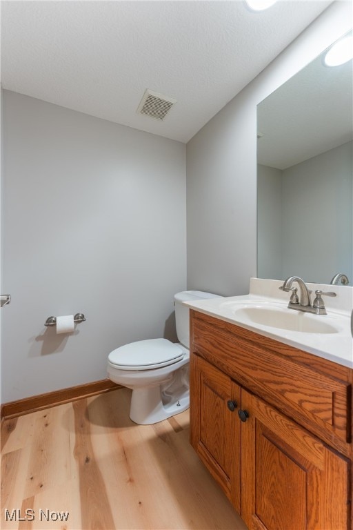 bathroom with vanity, toilet, and hardwood / wood-style floors