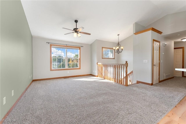 spare room with light colored carpet, ceiling fan with notable chandelier, and vaulted ceiling