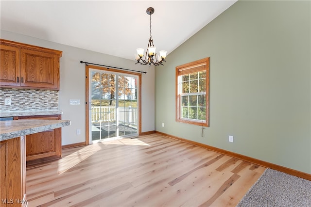 dining space with lofted ceiling, light hardwood / wood-style flooring, and an inviting chandelier