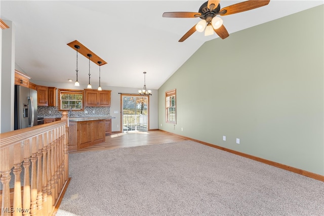 kitchen featuring stainless steel refrigerator with ice dispenser, sink, vaulted ceiling, decorative light fixtures, and tasteful backsplash