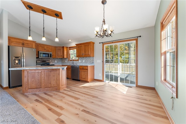 kitchen with appliances with stainless steel finishes, pendant lighting, and light hardwood / wood-style floors