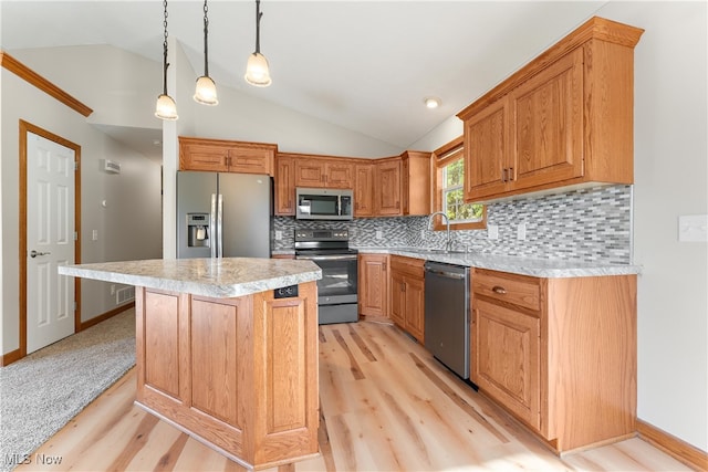 kitchen with vaulted ceiling, appliances with stainless steel finishes, hanging light fixtures, and light hardwood / wood-style floors