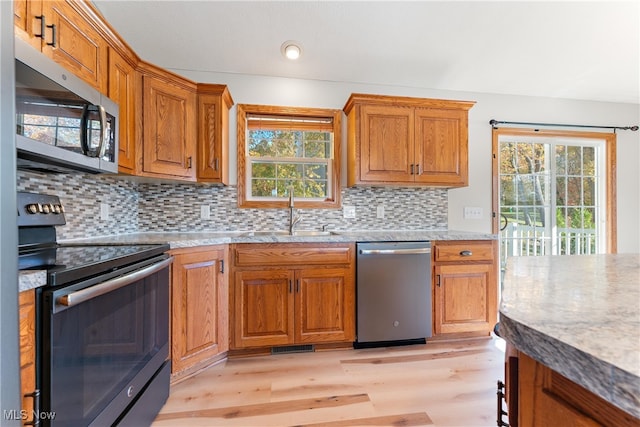 kitchen featuring sink, appliances with stainless steel finishes, light hardwood / wood-style floors, and tasteful backsplash