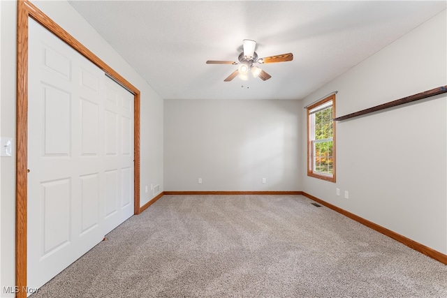 unfurnished bedroom with a closet, carpet, and ceiling fan