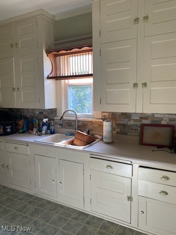 kitchen featuring crown molding, white cabinetry, sink, and tasteful backsplash