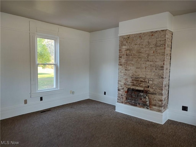 unfurnished living room with dark colored carpet, visible vents, and baseboards