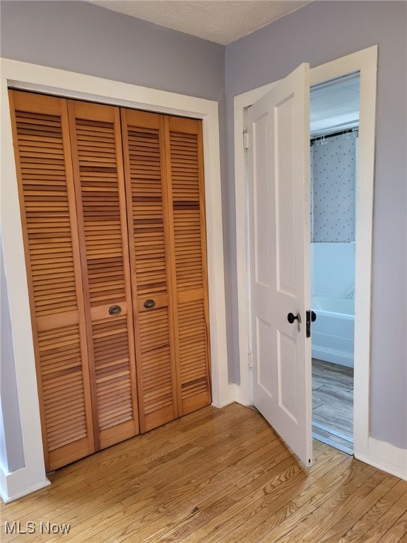 unfurnished bedroom featuring light wood-style flooring, a textured ceiling, and a closet