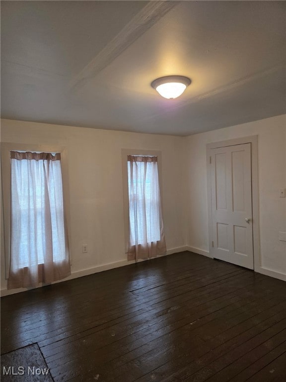 spare room with dark wood-style floors and baseboards