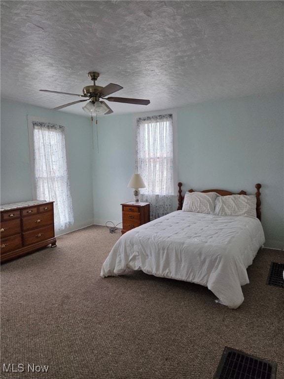 bedroom with multiple windows, a textured ceiling, and carpet flooring