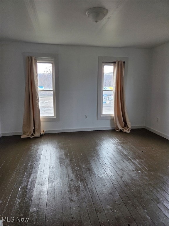 unfurnished room with a healthy amount of sunlight, dark wood finished floors, and baseboards