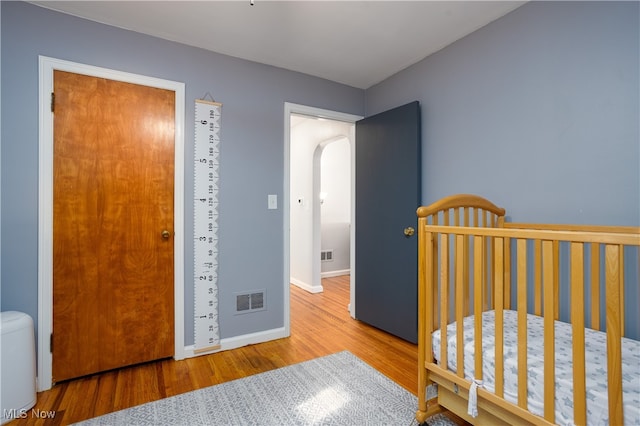 bedroom with hardwood / wood-style flooring and a nursery area