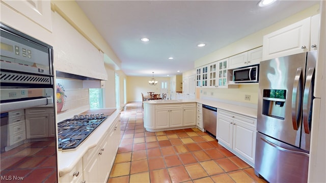 kitchen featuring appliances with stainless steel finishes, kitchen peninsula, pendant lighting, and white cabinets