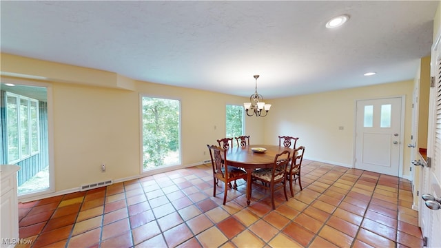 dining space with a healthy amount of sunlight, light tile patterned floors, and a chandelier