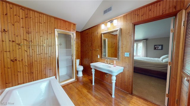 bathroom with lofted ceiling, hardwood / wood-style floors, toilet, and wooden walls