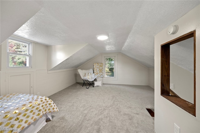 bedroom with lofted ceiling, light carpet, and a textured ceiling