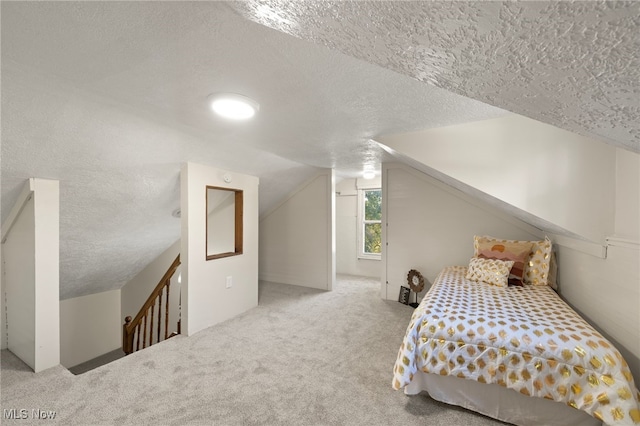 carpeted bedroom with a textured ceiling and vaulted ceiling