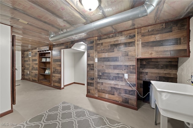 basement featuring wood walls and sink