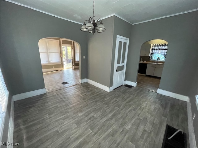 unfurnished dining area with sink, crown molding, a notable chandelier, and dark hardwood / wood-style flooring