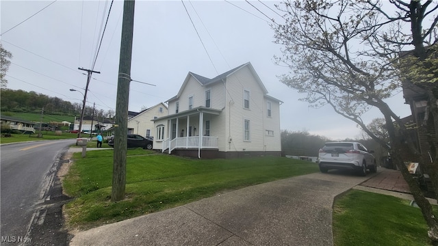 view of side of home with covered porch and a yard