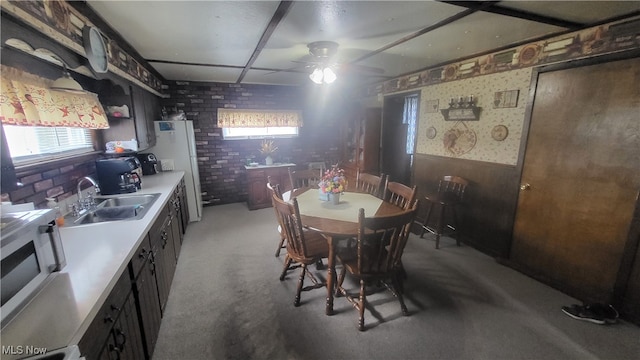 carpeted dining room with sink, brick wall, and ceiling fan