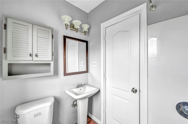 half bath featuring wood finished floors, a sink, and toilet
