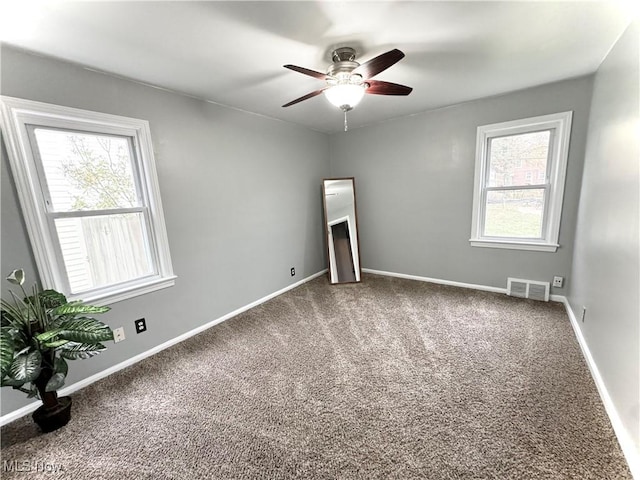 carpeted empty room with ceiling fan and a healthy amount of sunlight