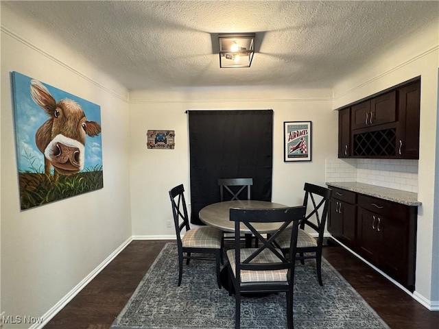 dining room featuring dark hardwood / wood-style flooring, a textured ceiling, and bar area