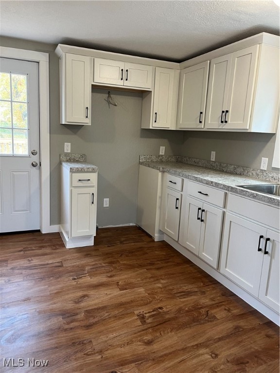 kitchen with sink, white cabinetry, a textured ceiling, and dark hardwood / wood-style flooring