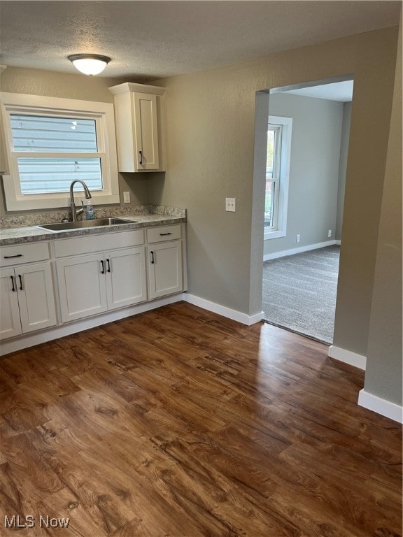 kitchen with white cabinetry, a textured ceiling, dark wood-type flooring, and sink