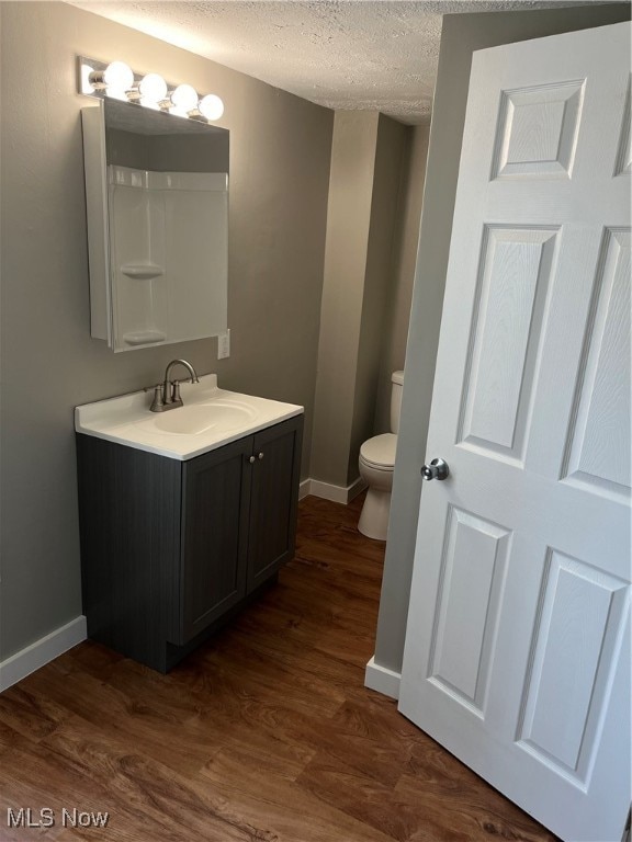 bathroom with vanity, hardwood / wood-style floors, a textured ceiling, and toilet