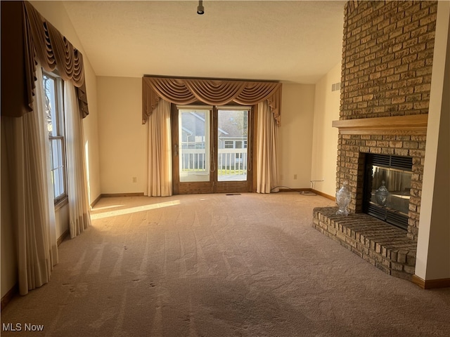 unfurnished living room featuring a textured ceiling, a fireplace, and light colored carpet