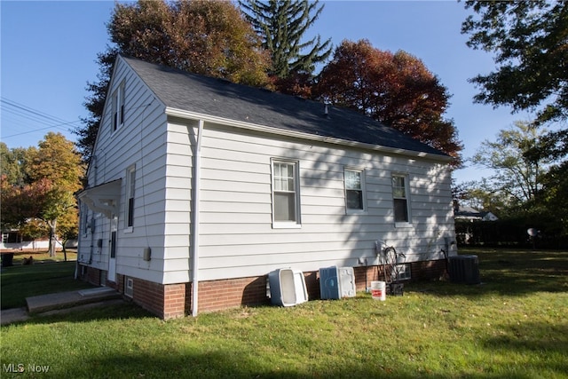 view of side of property with central air condition unit and a lawn