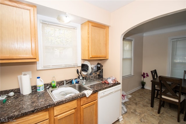 kitchen featuring white dishwasher, sink, light brown cabinets, and dark stone counters