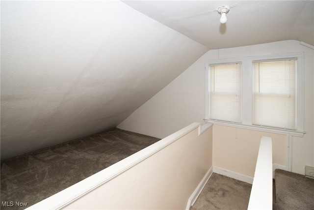 stairs with a textured ceiling, carpet, and lofted ceiling