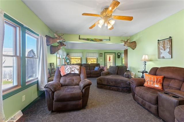 living room with ceiling fan, a wealth of natural light, and dark colored carpet