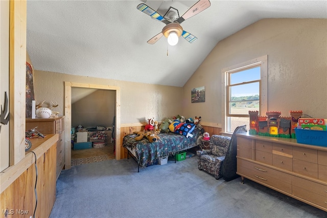 carpeted bedroom featuring ceiling fan, a textured ceiling, lofted ceiling, and wooden walls