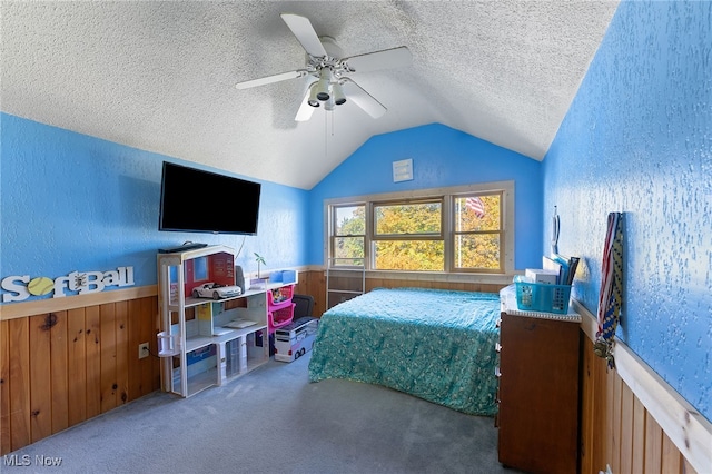 carpeted bedroom featuring ceiling fan, wood walls, a textured ceiling, and lofted ceiling