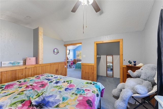 bedroom with ceiling fan, lofted ceiling, carpet flooring, and a textured ceiling