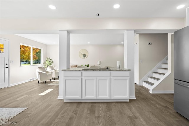 kitchen featuring light stone counters, freestanding refrigerator, a sink, light wood-style floors, and white cabinetry