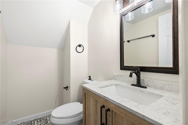 half bathroom featuring vanity, vaulted ceiling, toilet, and baseboards