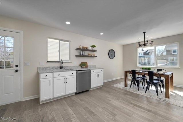 kitchen with dishwasher, light stone counters, light wood finished floors, and a sink