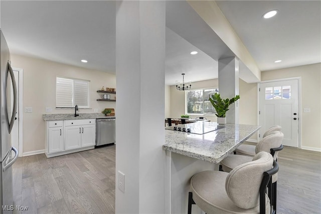 kitchen featuring white cabinets, appliances with stainless steel finishes, a breakfast bar, and light wood-style floors