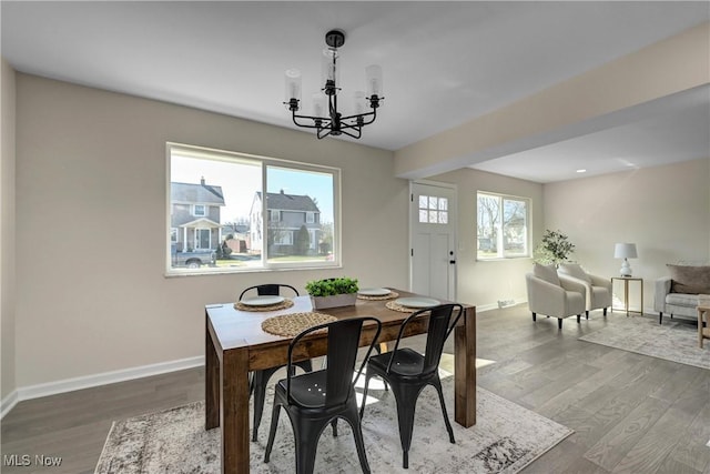 dining area featuring dark wood-type flooring, a notable chandelier, and baseboards