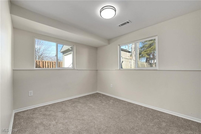 empty room with carpet flooring, baseboards, and visible vents