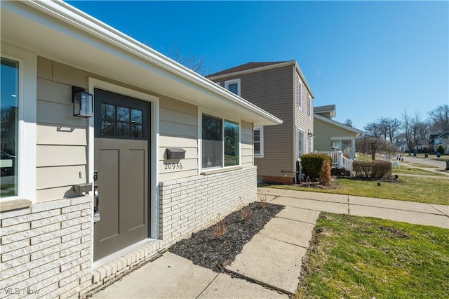 property entrance featuring brick siding and a lawn