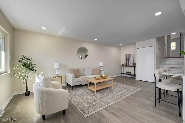 living room featuring recessed lighting, stairs, baseboards, and wood finished floors