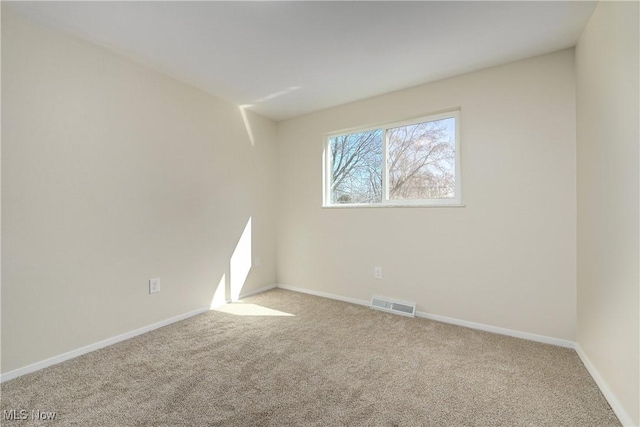 spare room featuring carpet, visible vents, and baseboards