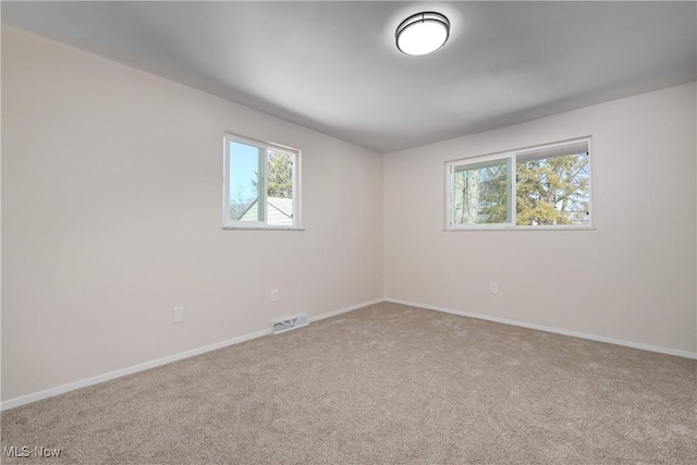 unfurnished room with visible vents, baseboards, and carpet