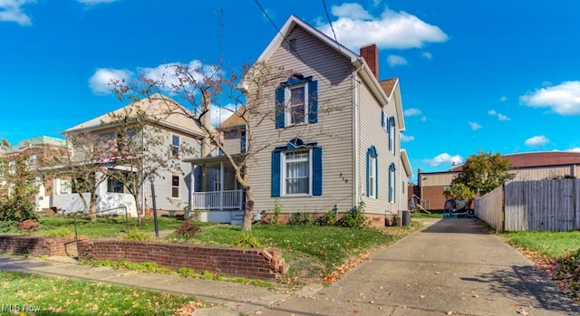 view of front of house featuring a front yard, central AC, fence, and a chimney